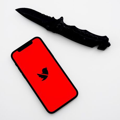 Ein Smartphone mit durchgestrichenem Twitter-Logo, daneben ein Kampfmesser.