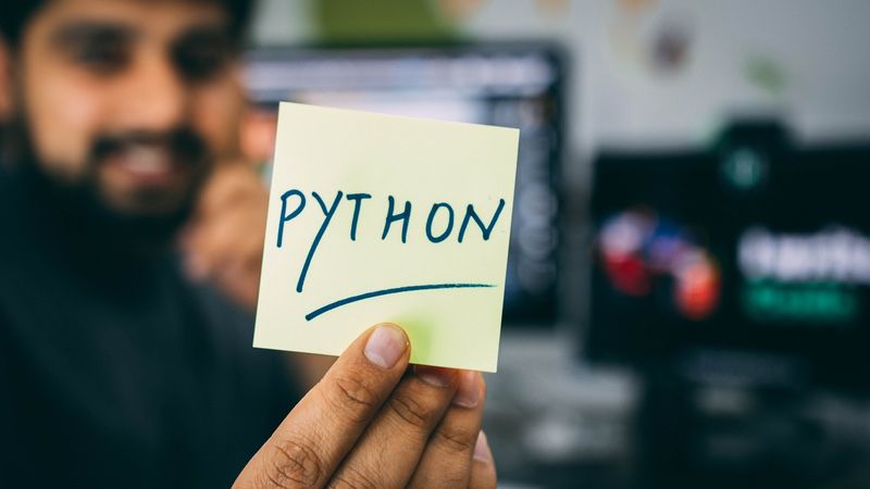 Programmierer der einen Zettel mit der Beschriftung »Python« hochhält.